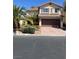 Two-story home with a tile roof, complemented by lush palm trees and desert landscaping at 10974 Fintry Hills St, Las Vegas, NV 89141