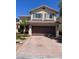 Two-story home featuring a tile roof and a brick paved driveway leading to a two car garage at 10974 Fintry Hills St, Las Vegas, NV 89141