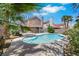 Lush backyard with a sparkling pool, mature trees, and vibrant greenery at 124 Wynntry Dr, Henderson, NV 89074