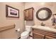 Charming powder room featuring wooden accents, a round mirror, and stone countertop at 1564 Fieldbrook St, Henderson, NV 89052