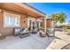Covered patio offers a cozy lounge area with ceiling fan, seating, and views of lush backyard at 1564 Fieldbrook St, Henderson, NV 89052
