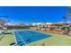 Outdoor tennis court under a blue sky with perimeter fencing, lighting, and seating for spectators at 2110 King Mesa Dr, Henderson, NV 89012