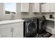 Functional laundry room featuring a sink, modern washer and dryer, and ample cabinet space for storage at 2153 King Crest Ct, Henderson, NV 89052