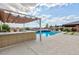 Outdoor kitchen and bar with shaded pergola overlooks the pool, spa, fire pit and nearby mountain views at 2153 King Crest Ct, Henderson, NV 89052