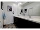 Bathroom boasting a double vanity sink, a large mirror, white walls and dark cabinets at 242 Polaris Ridge Ave, Henderson, NV 89011