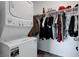 Walk in closet features a stacked washer dryer unit and hanging clothes at 242 Polaris Ridge Ave, Henderson, NV 89011
