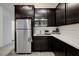 Modern kitchenette features stainless steel refrigerator, dark cabinets and white countertops at 242 Polaris Ridge Ave, Henderson, NV 89011