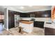Modern kitchen with dark wood cabinets, stainless steel appliances, island and stylish wood-look tile flooring at 2421 Sunrise Springs Ct, North Las Vegas, NV 89031