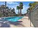 Community pool surrounded by palm trees and a metal fence at 2461 Old Forge Ln # 103, Las Vegas, NV 89121