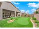 Spacious backyard with a putting green, lush landscaping, and a covered patio for outdoor dining at 2654 Summit Springs St, Henderson, NV 89044