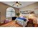 Comfortable bedroom features wood floors, natural light from an arch window, and simple decor at 2939 Crown Bluffs Ct, Las Vegas, NV 89117