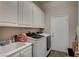 Well-equipped laundry room with modern washer and dryer, utility sink, and ample cabinet space at 2939 Crown Bluffs Ct, Las Vegas, NV 89117