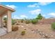 The desert landscape backyard features rock ground cover, mature bushes and a decorative rock stream at 4029 Ricebird Way, North Las Vegas, NV 89084