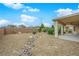 Large backyard featuring a covered patio and desert landscaping with a decorative rock drainage ditch at 4029 Ricebird Way, North Las Vegas, NV 89084