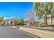 Gated community entrance showcasing lush landscaping and well-maintained residential buildings under a bright blue sky at 5710 E Tropicana Ave # 1017, Las Vegas, NV 89122