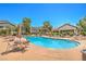 A large community pool featuring multiple seating areas, umbrellas, and lush tropical landscaping at 5710 E Tropicana Ave # 1017, Las Vegas, NV 89122