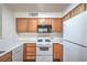 Bright kitchen features white appliances and countertops, and wood cabinets, with wood flooring at 5710 E Tropicana Ave # 1017, Las Vegas, NV 89122