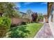 Beautiful backyard featuring lush green grass and mature landscaping, plus a brick patio along the home at 5713 Silver Cascade Ave, Las Vegas, NV 89131
