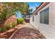 Home's side yard featuring desert landscaping, gravel, mature trees, and shrubbery at 5900 Red Umber Ave, Las Vegas, NV 89130