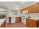 Bright kitchen boasts wood cabinetry, white appliances, a pass-through window, and tile floors at 5900 Red Umber Ave, Las Vegas, NV 89130