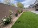 Lush backyard with artificial grass, flower bushes, and a brick privacy wall, creating a private retreat at 7527 Ardenno St, North Las Vegas, NV 89084