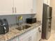 Modern kitchen featuring granite countertops, white cabinets, and stainless steel appliances at 7527 Ardenno St, North Las Vegas, NV 89084