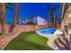 Lush backyard with artificial grass and sparkling blue swimming pool at 7616 Gossamer Wind St, Las Vegas, NV 89139