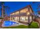 A backyard featuring a sparkling pool, manicured lawn, and a two-story patio area for outdoor entertaining at 7616 Gossamer Wind St, Las Vegas, NV 89139