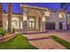 Beautiful front entrance with a brick walkway, manicured lawn, and a three car garage at 7616 Gossamer Wind St, Las Vegas, NV 89139