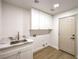Laundry room with custom cabinets, sink, and light wood floors at 7616 Gossamer Wind St, Las Vegas, NV 89139