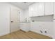 Clean and functional laundry room with white cabinets, gold faucet, and wood-style flooring at 7616 Gossamer Wind St, Las Vegas, NV 89139