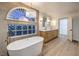 Bright main bathroom with a soaking tub, glass block window, and double vanity at 7616 Gossamer Wind St, Las Vegas, NV 89139