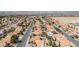 Expansive view of a desert neighborhood with lush landscaping, tile roofs, and mountain views at 8326 Mount Nido Dr, Las Vegas, NV 89147