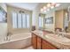 Bright bathroom with dual sinks, granite countertops, plantation shutters, and a soaking tub at 10314 Premia Pl, Las Vegas, NV 89135