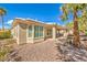 Exterior view of the house with a covered patio, lush landscaping, and rock features in the backyard with palm trees at 10314 Premia Pl, Las Vegas, NV 89135