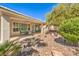 Relaxing covered patio with ample seating, an outdoor grill, and a beautifully landscaped backyard with lush greenery and rock features at 10314 Premia Pl, Las Vegas, NV 89135