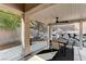 Covered patio features a dining table, ceiling fan, and outdoor kitchen with lush backyard views at 10410 Nostalgia Cir, Las Vegas, NV 89135