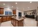 Open concept kitchen with kitchen island, wood cabinets, and tile flooring, with living room views at 11345 Espadrille Ct, Las Vegas, NV 89138