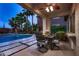 Covered patio featuring an outdoor dining set, lush landscaping, and view of the pool area at 11345 Espadrille Ct, Las Vegas, NV 89138