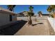 Large dirt backyard featuring palm trees, desert foliage, and white and concrete fencing at 1214 Emerald Stone Ave, North Las Vegas, NV 89081