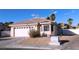 Exterior elevation of a beige house featuring a driveway and desert landscaping at 1214 Emerald Stone Ave, North Las Vegas, NV 89081