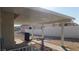 Covered patio featuring a concrete walkway, beige siding, white fencing, and tan rock landscaping at 1214 Emerald Stone Ave, North Las Vegas, NV 89081