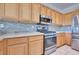 Kitchen featuring stainless steel appliances, stone backsplash, and wooden cabinets at 1613 Williamsport St, Henderson, NV 89052