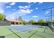 Bright blue outdoor tennis court featuring a green surround and a nearby clubhouse with seating, perfect for enjoying a match at 1613 Williamsport St, Henderson, NV 89052