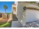 Side angle view of a two-story home with stucco walls, a two-car garage, and a well-manicured lawn at 1672 Cloister Ave, Henderson, NV 89014