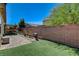 A brick wall surrounds a well-maintained backyard with artificial turf, a patio, and lush landscaping at 2425 Amatrice St, Henderson, NV 89044