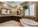 Bright bathroom with dual sinks, dark wood cabinets, and a soaking tub at 2425 Amatrice St, Henderson, NV 89044