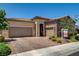 Charming single-story home features a tiled roof, desert landscaping, and a brick-paved driveway leading to a two-car garage at 2425 Amatrice St, Henderson, NV 89044