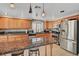 Cozy kitchen with tile floors, wood cabinetry, stainless appliances, granite countertops, and modern lighting at 2429 Sun Shores Dr, Las Vegas, NV 89128