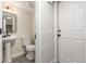 Bathroom with pedestal sink, toilet, mirror, and white walls, next to a white paneled door at 2451 Old Forge Ln # 105, Las Vegas, NV 89121